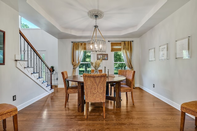 dining area featuring a raised ceiling, dark hardwood / wood-style floors, and a chandelier