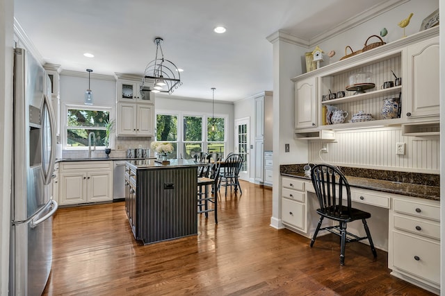 kitchen with a kitchen bar, hanging light fixtures, dark hardwood / wood-style floors, and stainless steel appliances