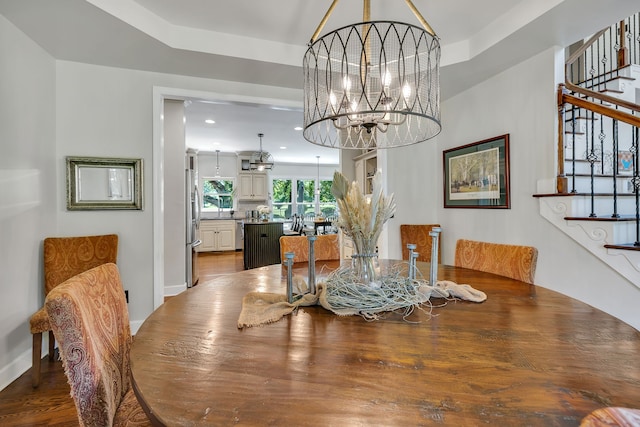 dining room with a notable chandelier, dark hardwood / wood-style floors, and a tray ceiling