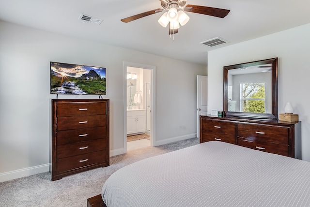 bedroom featuring ceiling fan, light colored carpet, and ensuite bath