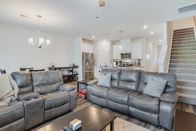 living room with ceiling fan with notable chandelier, sink, and hardwood / wood-style flooring