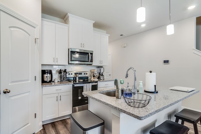 kitchen with hanging light fixtures, tasteful backsplash, dark wood-type flooring, stainless steel appliances, and white cabinets