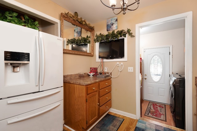 foyer featuring an inviting chandelier, washer / dryer, and light hardwood / wood-style floors