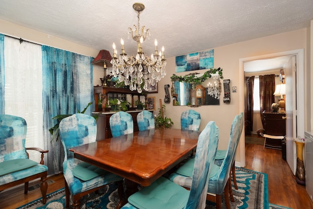 dining space with dark hardwood / wood-style floors, a textured ceiling, and a notable chandelier