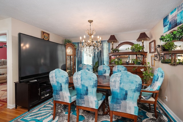 dining area featuring an inviting chandelier, a textured ceiling, and light hardwood / wood-style flooring