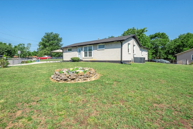 back of house with central AC and a lawn