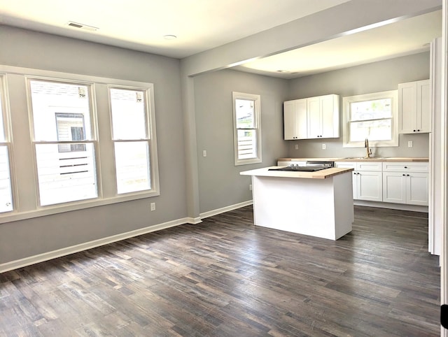 kitchen with dark hardwood / wood-style floors, a healthy amount of sunlight, a center island, and white cabinetry