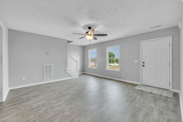 empty room with ceiling fan, a textured ceiling, and light wood-type flooring