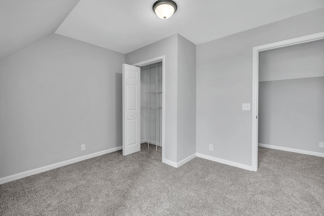 unfurnished bedroom featuring a closet, dark colored carpet, and vaulted ceiling