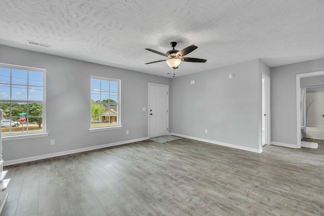 spare room with ceiling fan, a textured ceiling, light hardwood / wood-style floors, and plenty of natural light