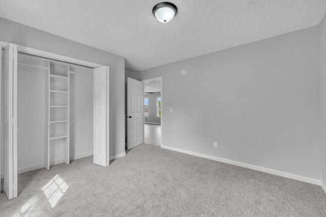 unfurnished bedroom with a closet, light colored carpet, and a textured ceiling