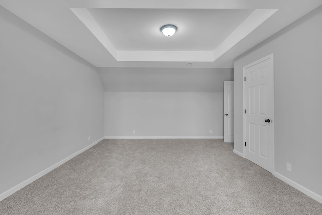 carpeted empty room featuring a raised ceiling