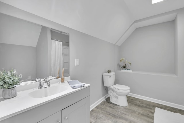 bathroom featuring toilet, vanity, hardwood / wood-style flooring, and vaulted ceiling