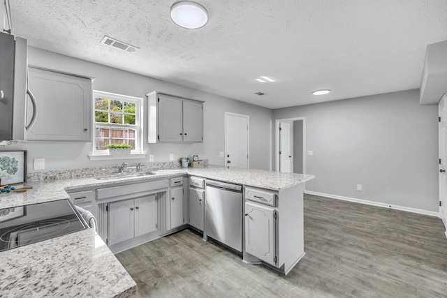 kitchen with hardwood / wood-style flooring, stainless steel dishwasher, kitchen peninsula, gray cabinets, and sink