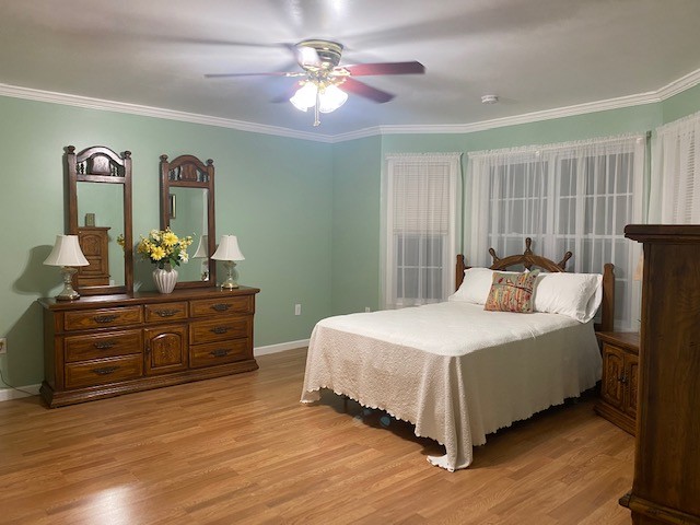 bedroom featuring ceiling fan, light hardwood / wood-style flooring, and ornamental molding