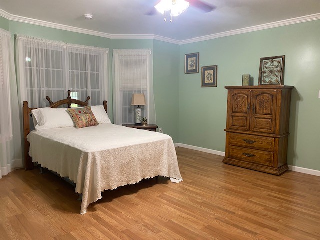 bedroom featuring ceiling fan, ornamental molding, and light hardwood / wood-style flooring