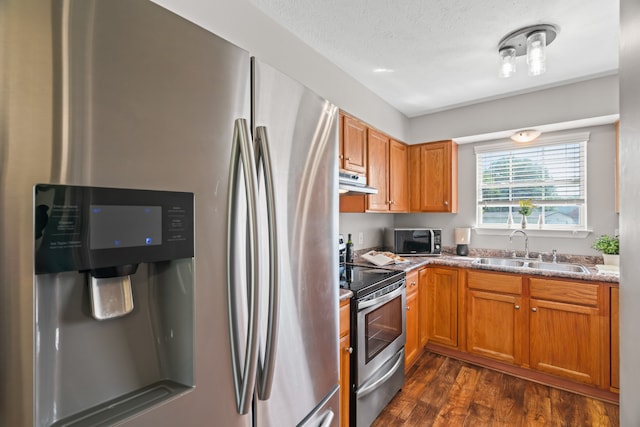 kitchen featuring dark hardwood / wood-style floors, sink, light stone counters, appliances with stainless steel finishes, and a textured ceiling