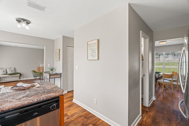 kitchen with stainless steel appliances, a textured ceiling, and dark hardwood / wood-style flooring