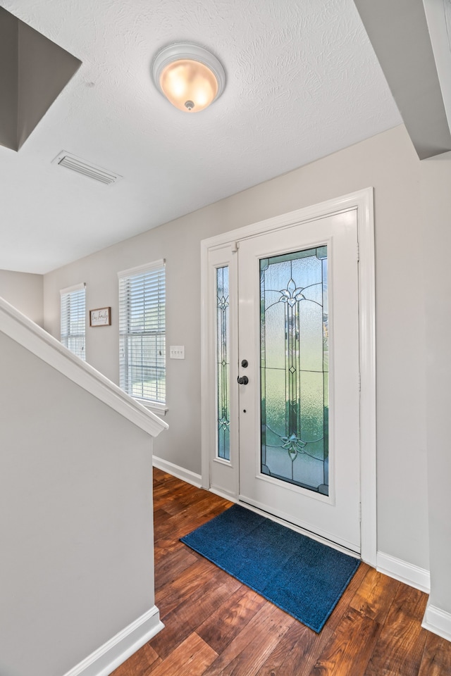 foyer featuring a textured ceiling and dark wood-type flooring