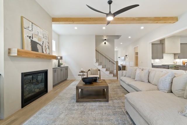 living room featuring ceiling fan, beam ceiling, and light hardwood / wood-style floors