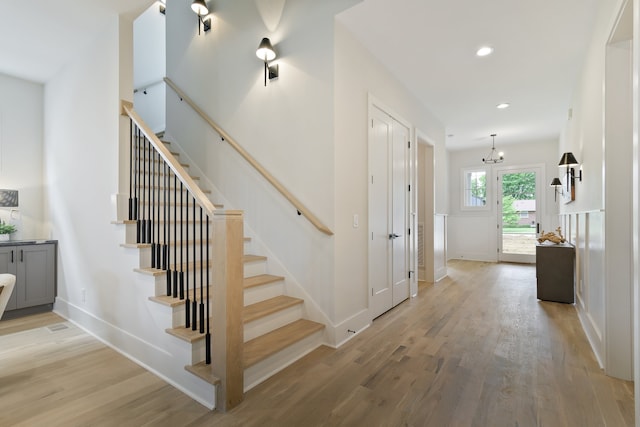 stairs with a notable chandelier and light hardwood / wood-style floors