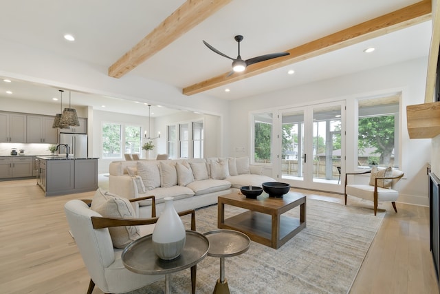 living room with french doors, sink, beamed ceiling, light hardwood / wood-style floors, and ceiling fan with notable chandelier