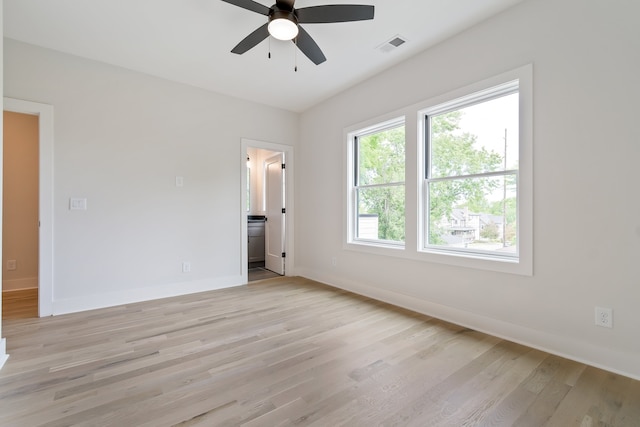 unfurnished bedroom featuring ceiling fan, connected bathroom, light hardwood / wood-style floors, and multiple windows