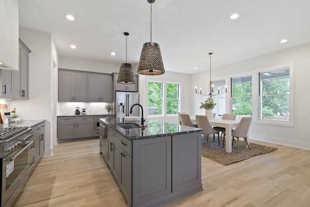 kitchen featuring hanging light fixtures, light hardwood / wood-style floors, appliances with stainless steel finishes, and an inviting chandelier