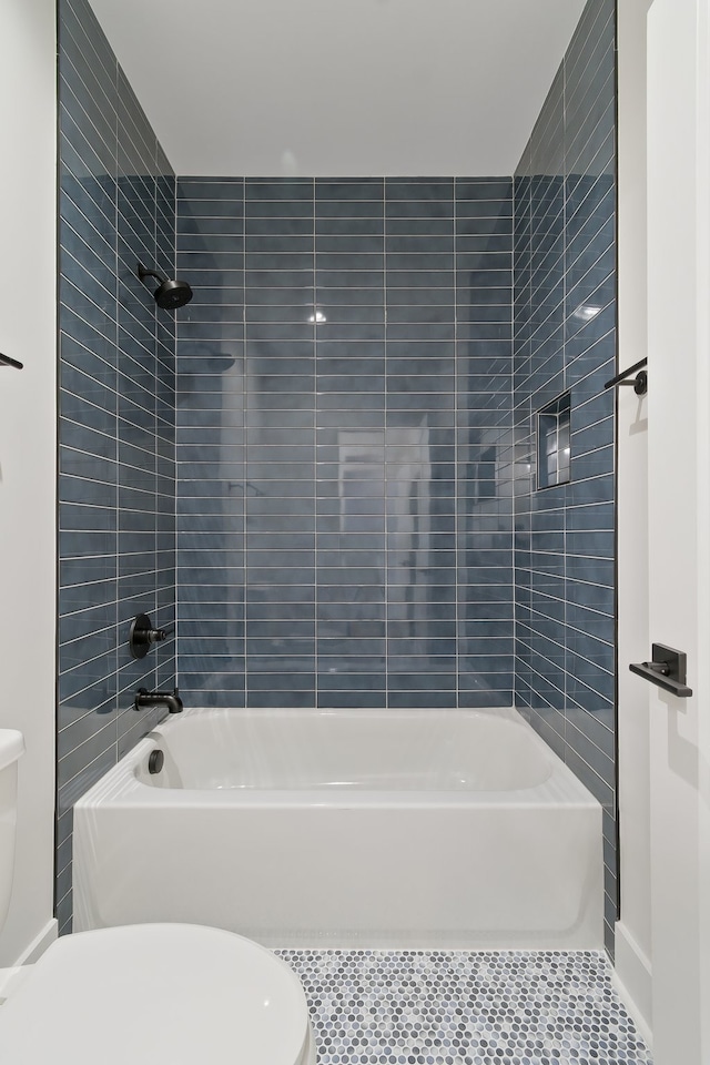 bathroom with tile flooring, toilet, and tiled shower / bath combo