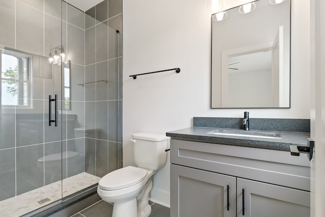 bathroom featuring toilet, vanity with extensive cabinet space, tile flooring, and a shower with door