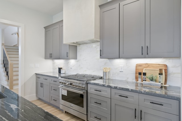 kitchen with light hardwood / wood-style floors, dark stone countertops, high end range, and custom exhaust hood