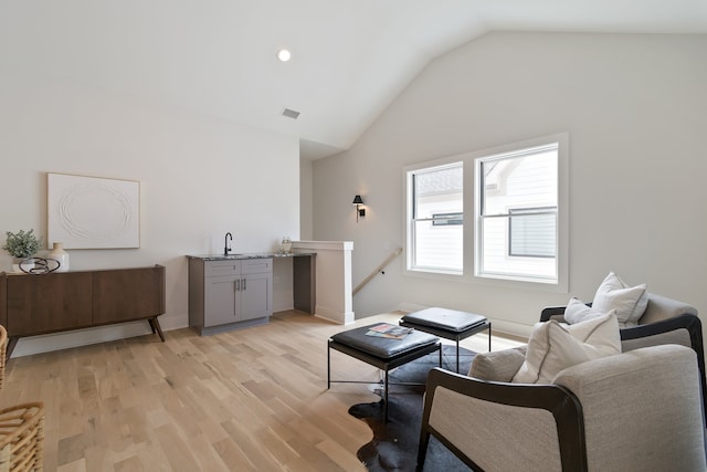 sitting room with vaulted ceiling, light wood-type flooring, and sink