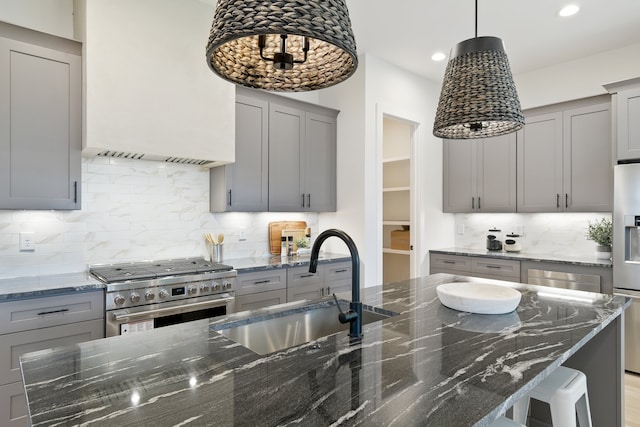 kitchen featuring backsplash, gray cabinetry, stainless steel appliances, and dark stone countertops