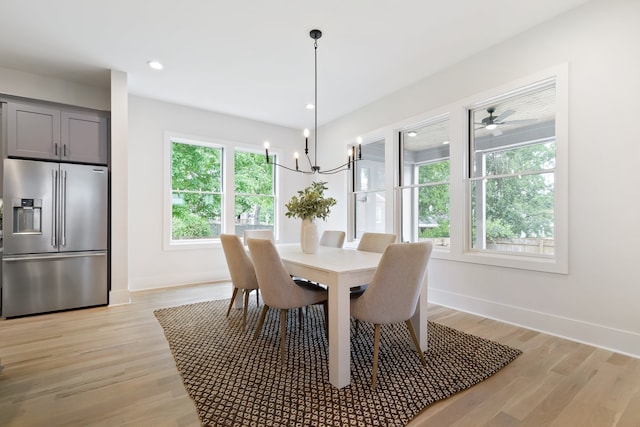 dining area with light hardwood / wood-style floors and ceiling fan with notable chandelier