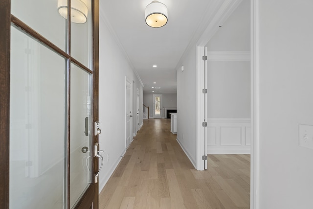 hallway with ornamental molding and light wood-type flooring