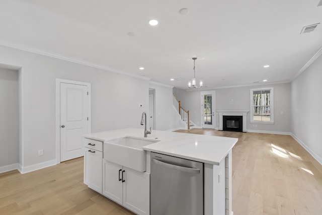 kitchen with an inviting chandelier, light hardwood / wood-style floors, white cabinetry, stainless steel dishwasher, and a kitchen island with sink