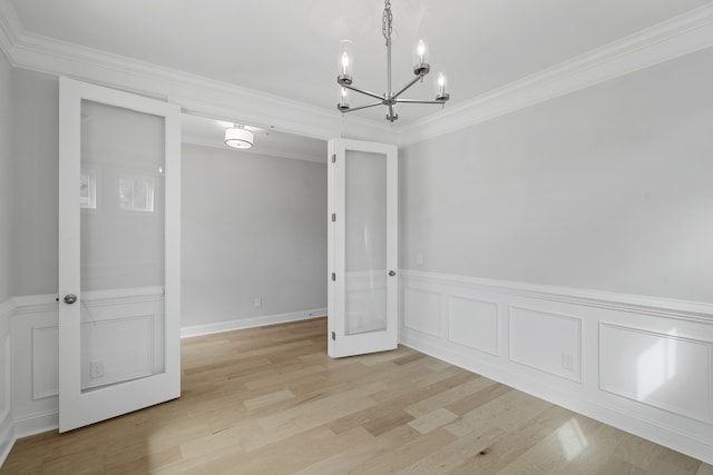 spare room featuring a notable chandelier, light hardwood / wood-style flooring, and ornamental molding