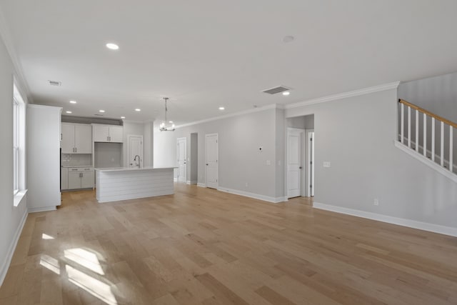 unfurnished living room with a notable chandelier, crown molding, and light hardwood / wood-style flooring