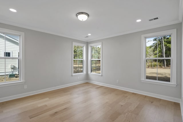 spare room featuring ornamental molding, light wood-type flooring, and plenty of natural light