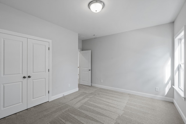 unfurnished bedroom featuring light colored carpet and a closet