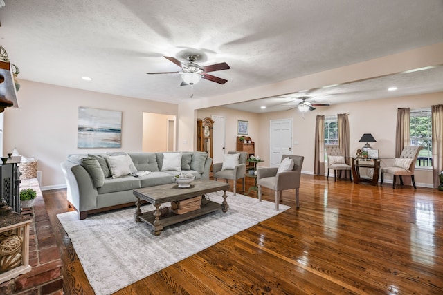 living room with a textured ceiling, ceiling fan, and dark hardwood / wood-style flooring