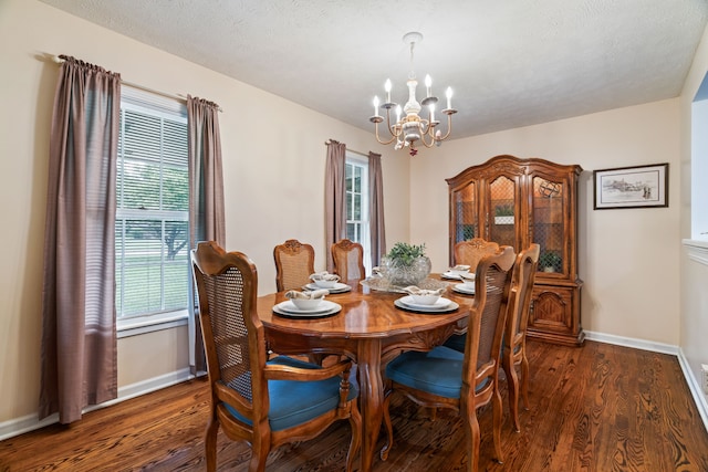 dining area with an inviting chandelier, dark wood-type flooring, and a textured ceiling