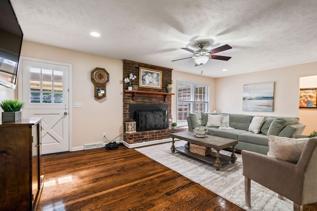 living room featuring hardwood / wood-style floors, a textured ceiling, a fireplace, and ceiling fan