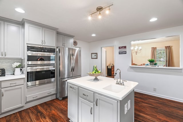 kitchen featuring appliances with stainless steel finishes, dark wood-type flooring, a notable chandelier, sink, and gray cabinets