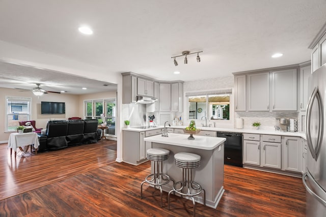 kitchen featuring dark wood-type flooring, an island with sink, ceiling fan, gray cabinets, and black appliances