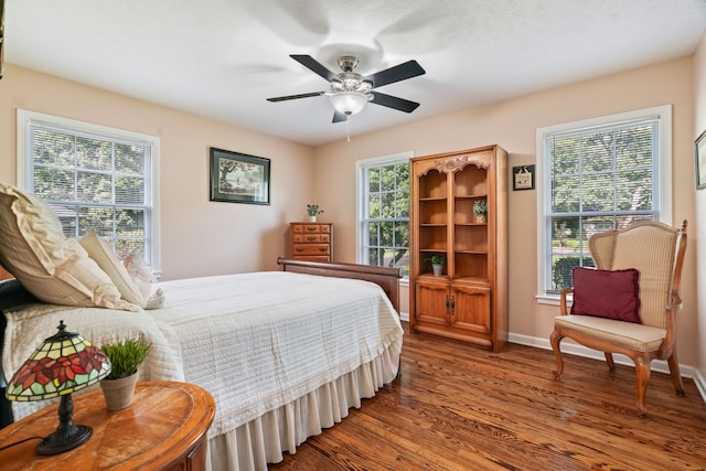 bedroom featuring ceiling fan, dark wood-type flooring, and multiple windows