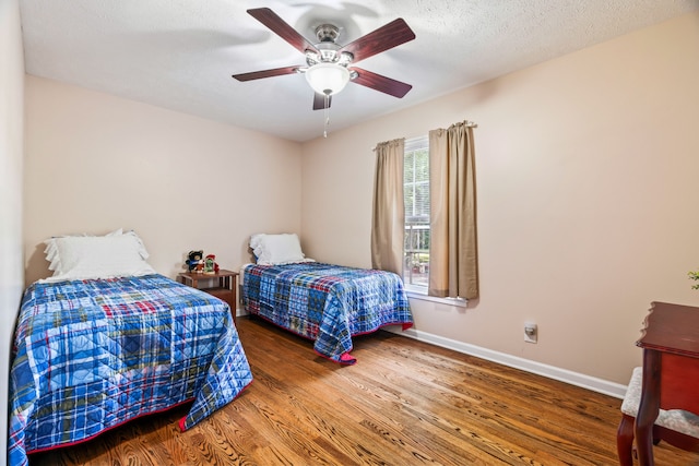 bedroom with a textured ceiling, ceiling fan, and dark wood-type flooring