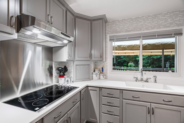 kitchen featuring gray cabinetry, backsplash, sink, and black electric stovetop