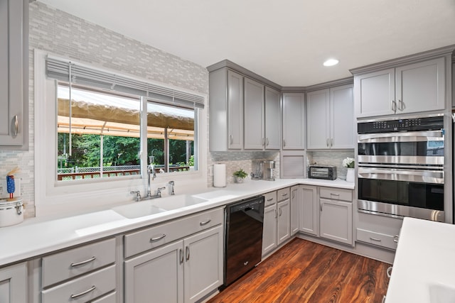 kitchen featuring dark wood-type flooring, tasteful backsplash, gray cabinets, double oven, and sink