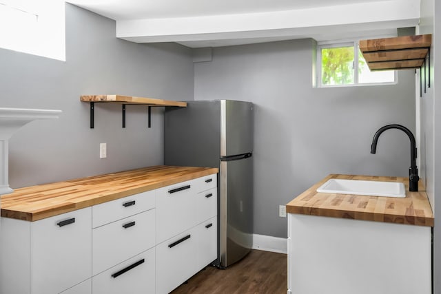 kitchen featuring wooden counters, dark hardwood / wood-style flooring, white cabinetry, and sink